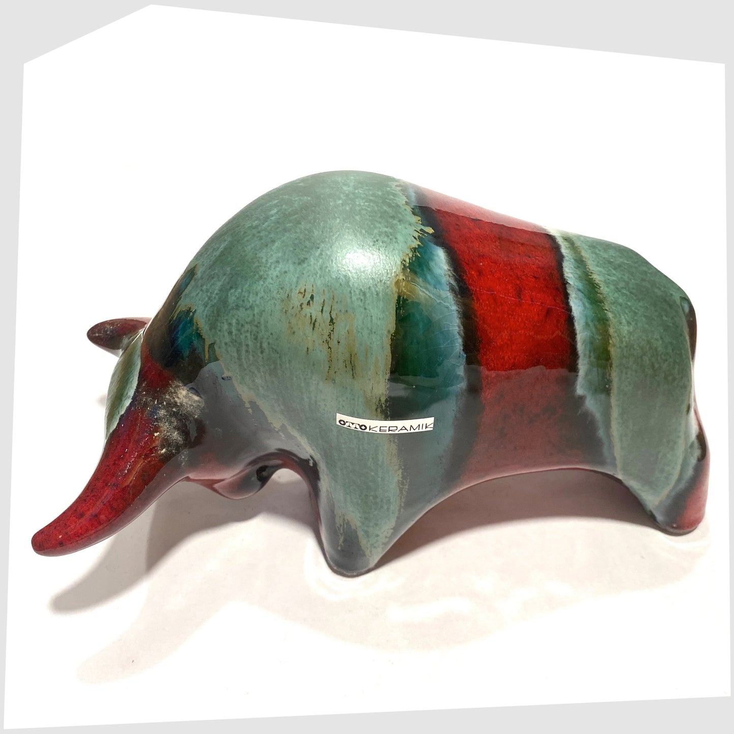 Rear spine of the Otto Keramik Bull in Bolivia glaze of deep red with stripes of rich sea green, shown on a white background