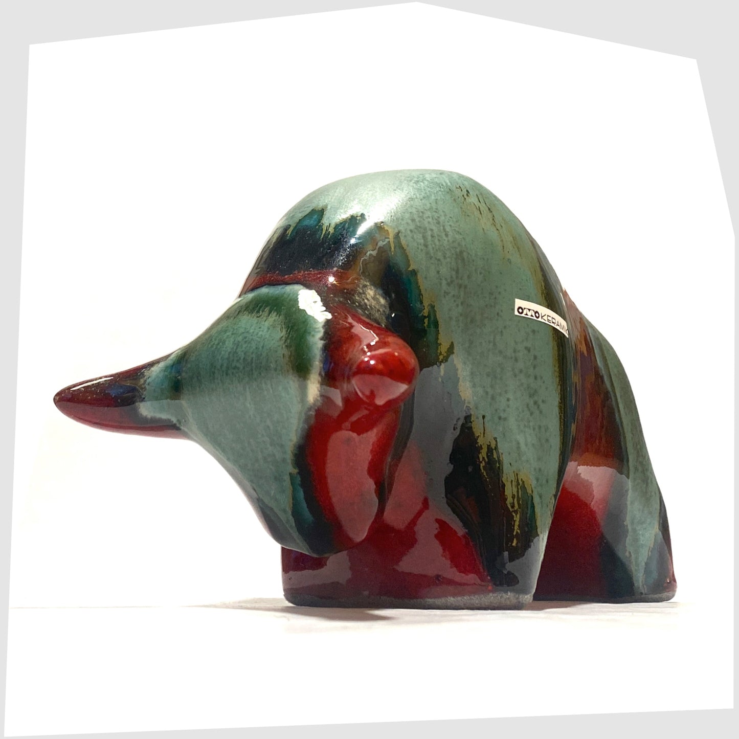 Front horns of the Otto Keramik Bull in Bolivia glaze of deep red with stripes of rich sea green, shown on a white background