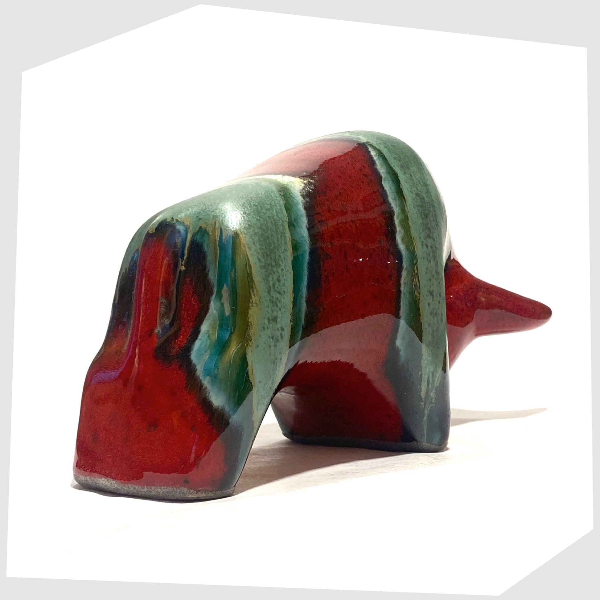 Rear of the Otto Keramik Bull in Bolivia glaze of deep red with stripes of rich sea green, shown on a white background