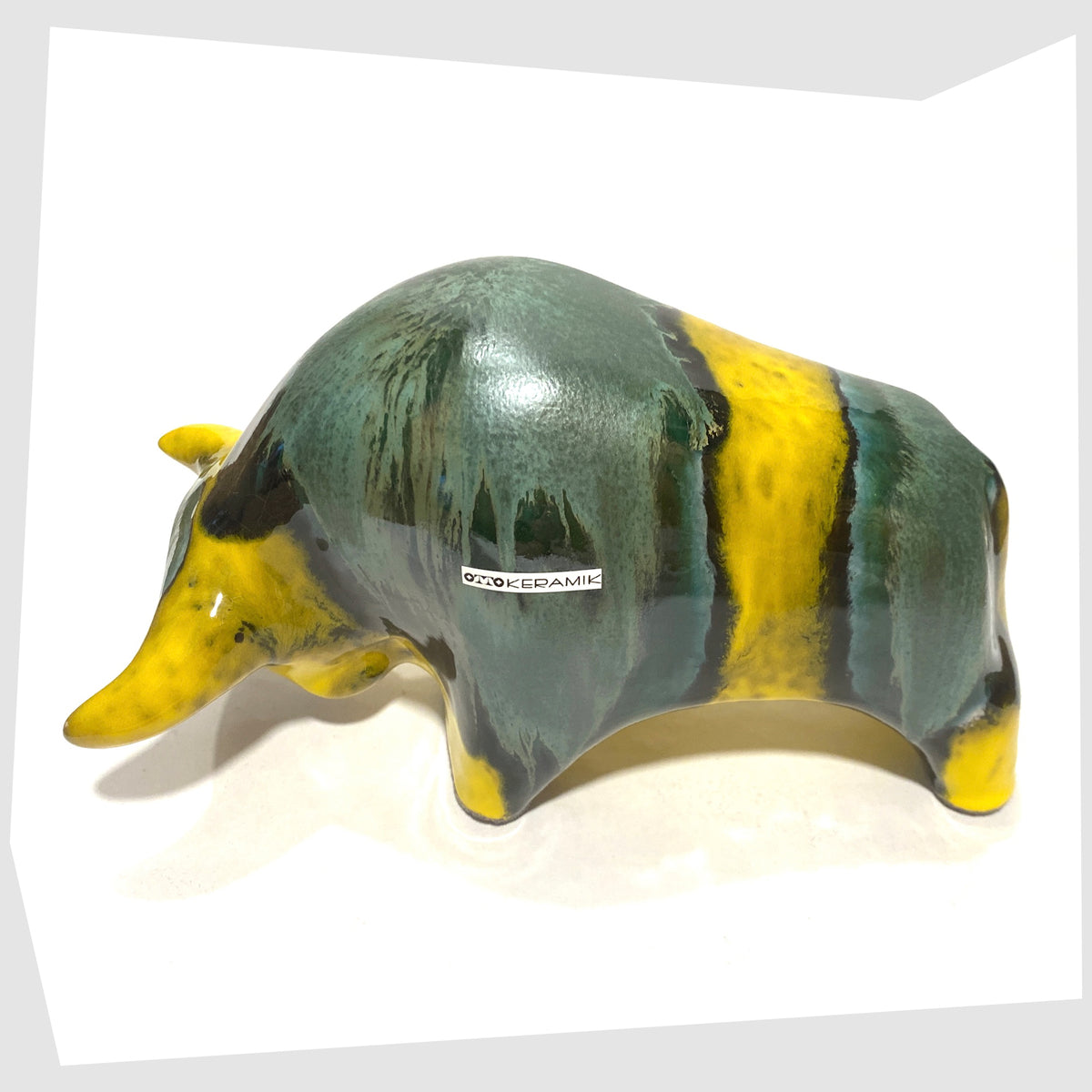 Back of the Otto Keramik Ceramic Bull in Brazil Glaze of yellow and sea green stripes, shown on a white background