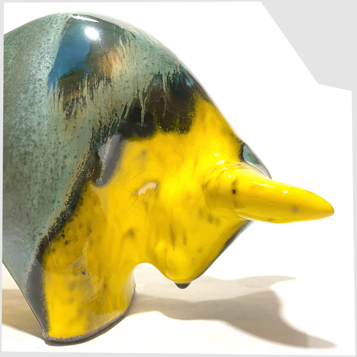 Close up of the front section of the Otto Keramik Ceramic Bull in Brazil Glaze of yellow and sea green stripes, shown on a white background