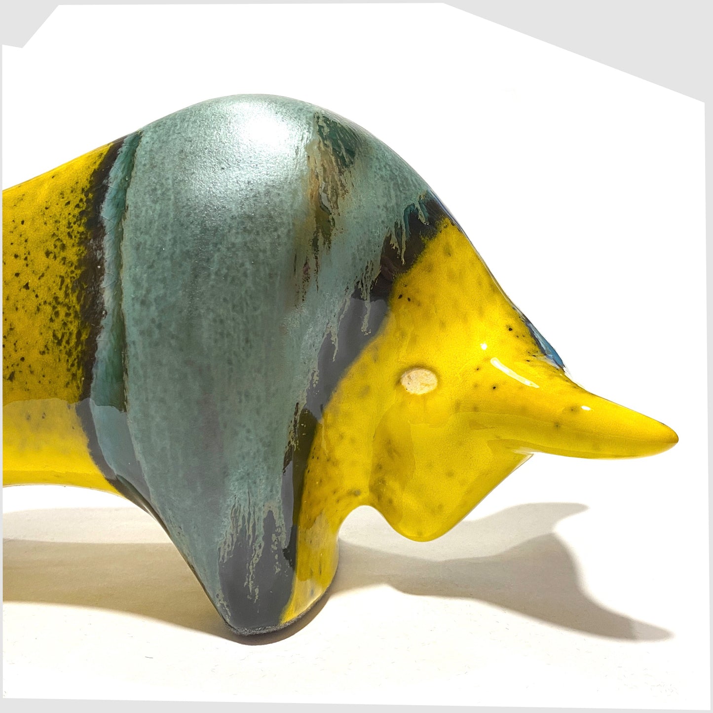 close up of the otto keramik bull ornament in brazil glaze of yellow and sea green glaze