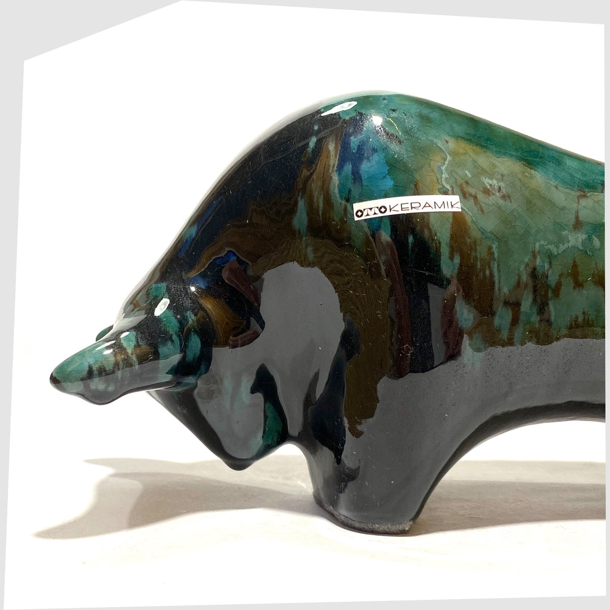 Close up of the Otto Keramik Bull in Ecuador glaze of gloss black and teal, shown on a white background