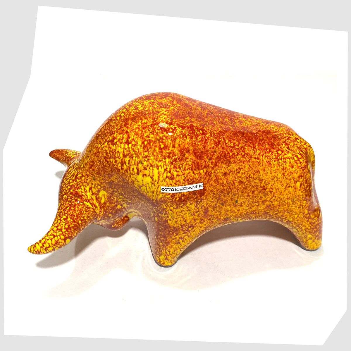 Overhead view of the Otto Keramik Bull in fire glaze of red, orange and yellow flecks, shown on a white background