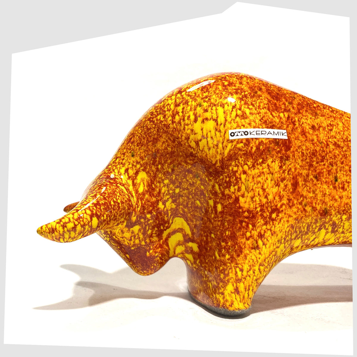 Close up of the Otto Keramik Bull in fire glaze of red, orange and yellow flecks, shown on a white background