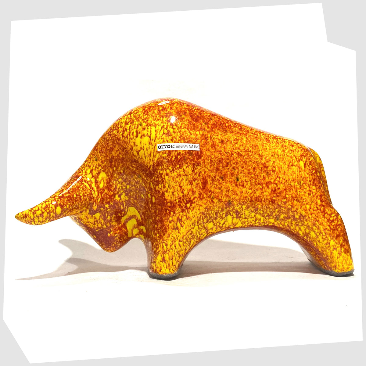 Otto Keramik Bull in fire glaze of red, orange and yellow flecks, shown on a white background