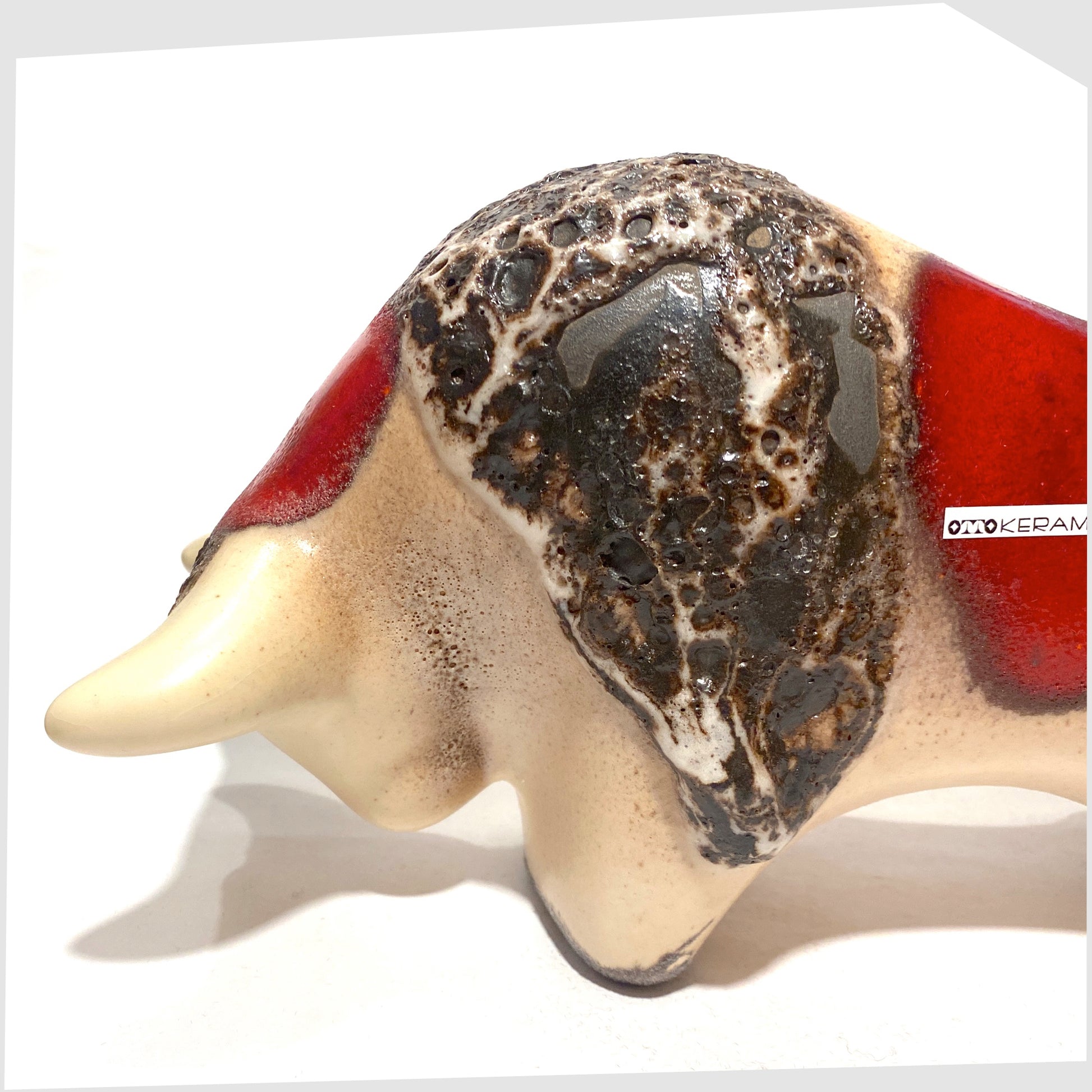 close up of the otto keramik ceramic bull shaped ornament in the red garnet glaze with stripes of deep fat lava