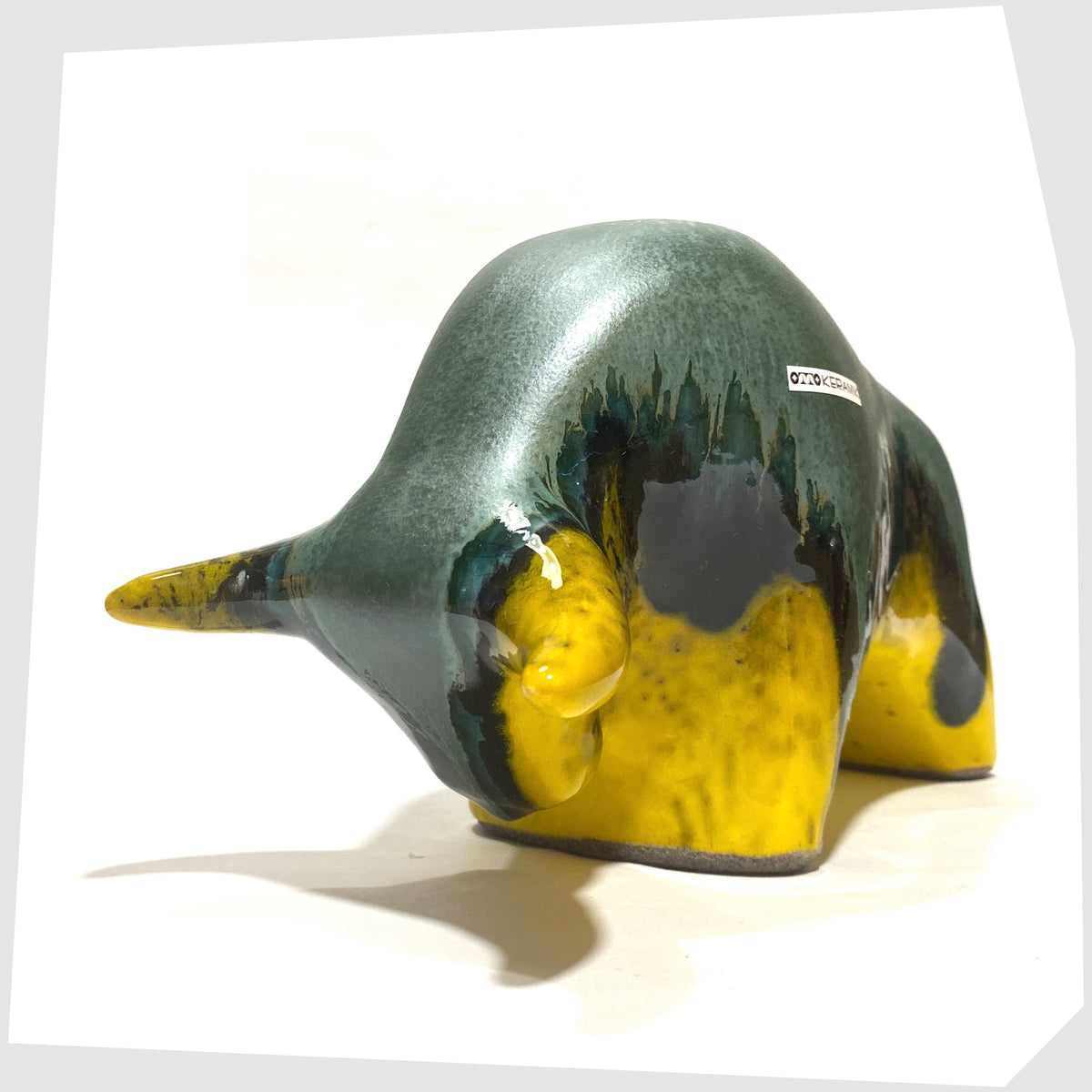 Front of the Otto Keramik ceramic bull-shaped sculpture in green over yellow drip glaze, shown on a white background