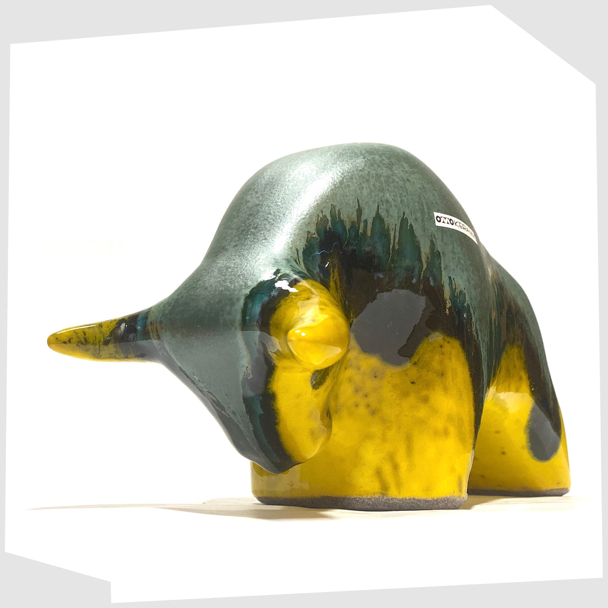 Front horns of the Otto Keramik ceramic bull-shaped sculpture in green over yellow drip glaze, shown on a white background