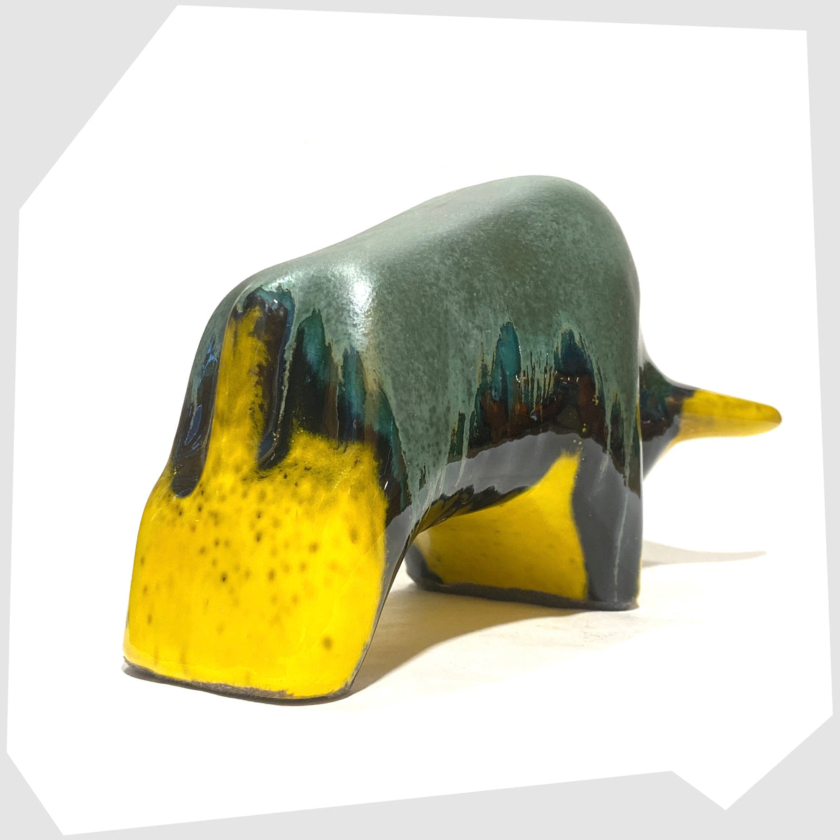 Rear of the Otto Keramik ceramic bull-shaped sculpture in green over yellow drip glaze, shown on a white background