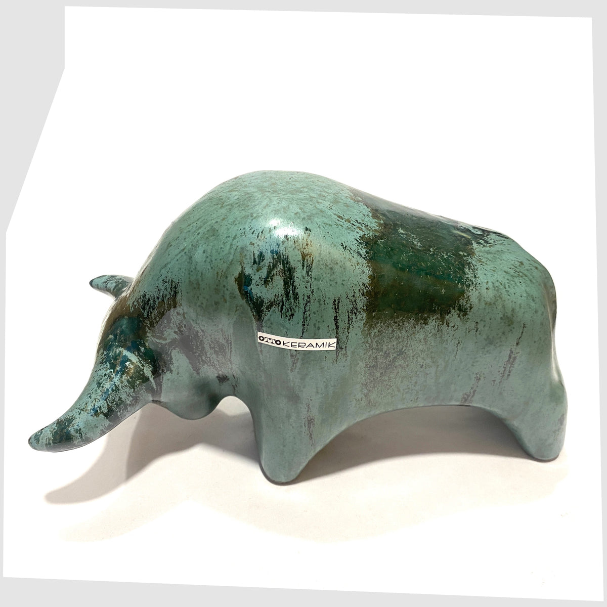 Overhead view of the Otto Keramik Bull shaped figurine in Malta glaze of rich sea green with darker drip glazing, shown on a white background