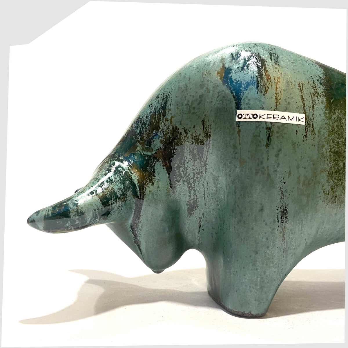 Front section of the Otto Keramik Bull shaped figurine in Malta glaze of rich sea green with darker drip glazing, shown on a white background
