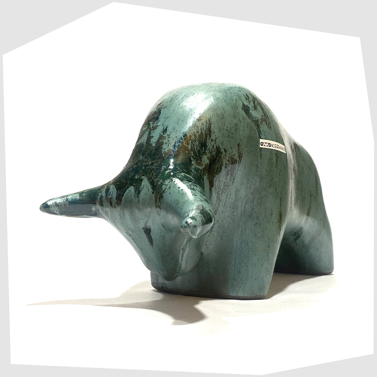 Front of the Otto Keramik Bull shaped figurine in Malta glaze of rich sea green with darker drip glazing, shown on a white background