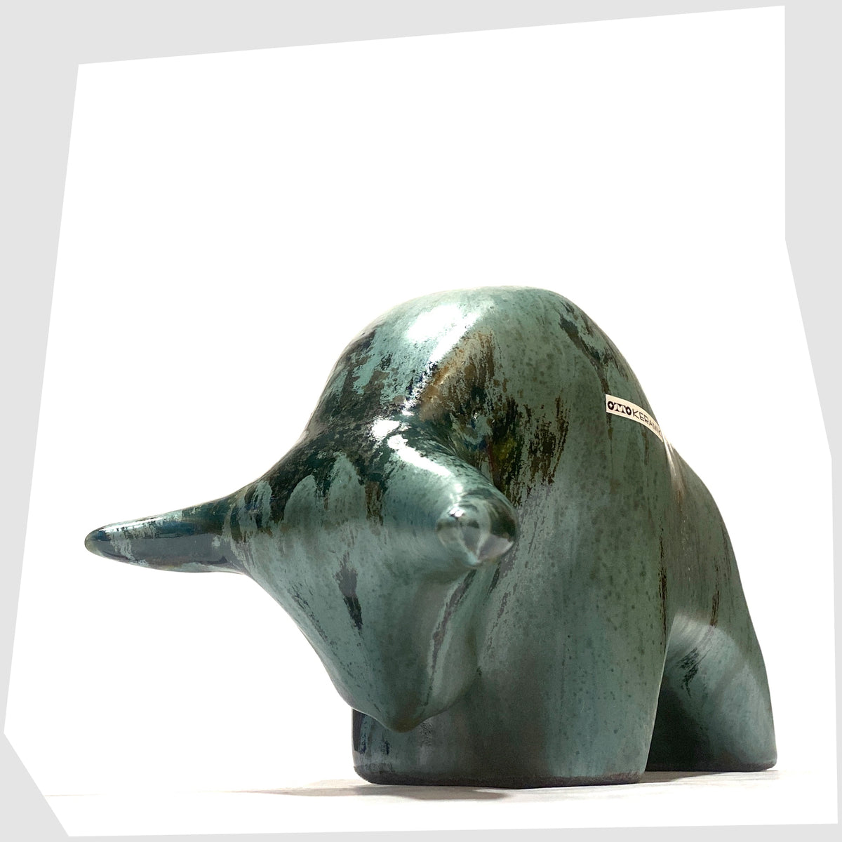Front horns of the Otto Keramik Bull shaped figurine in Malta glaze of rich sea green with darker drip glazing, shown on a white background