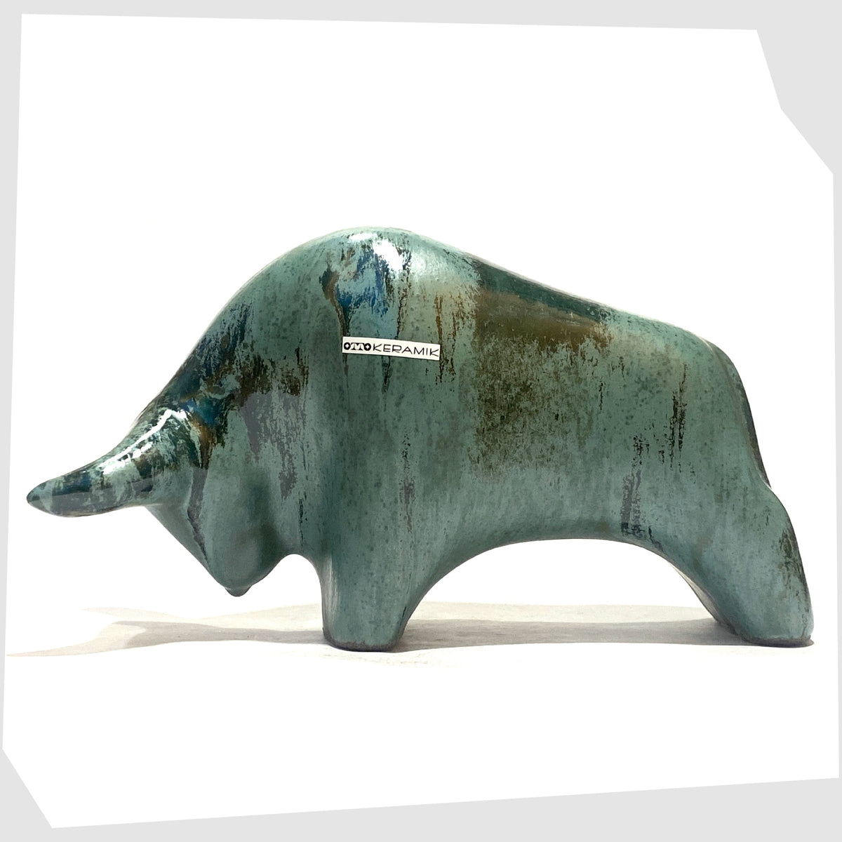 Otto Keramik Bull shaped figurine in Malta glaze of rich sea green with darker drip glazing, shown on a white background