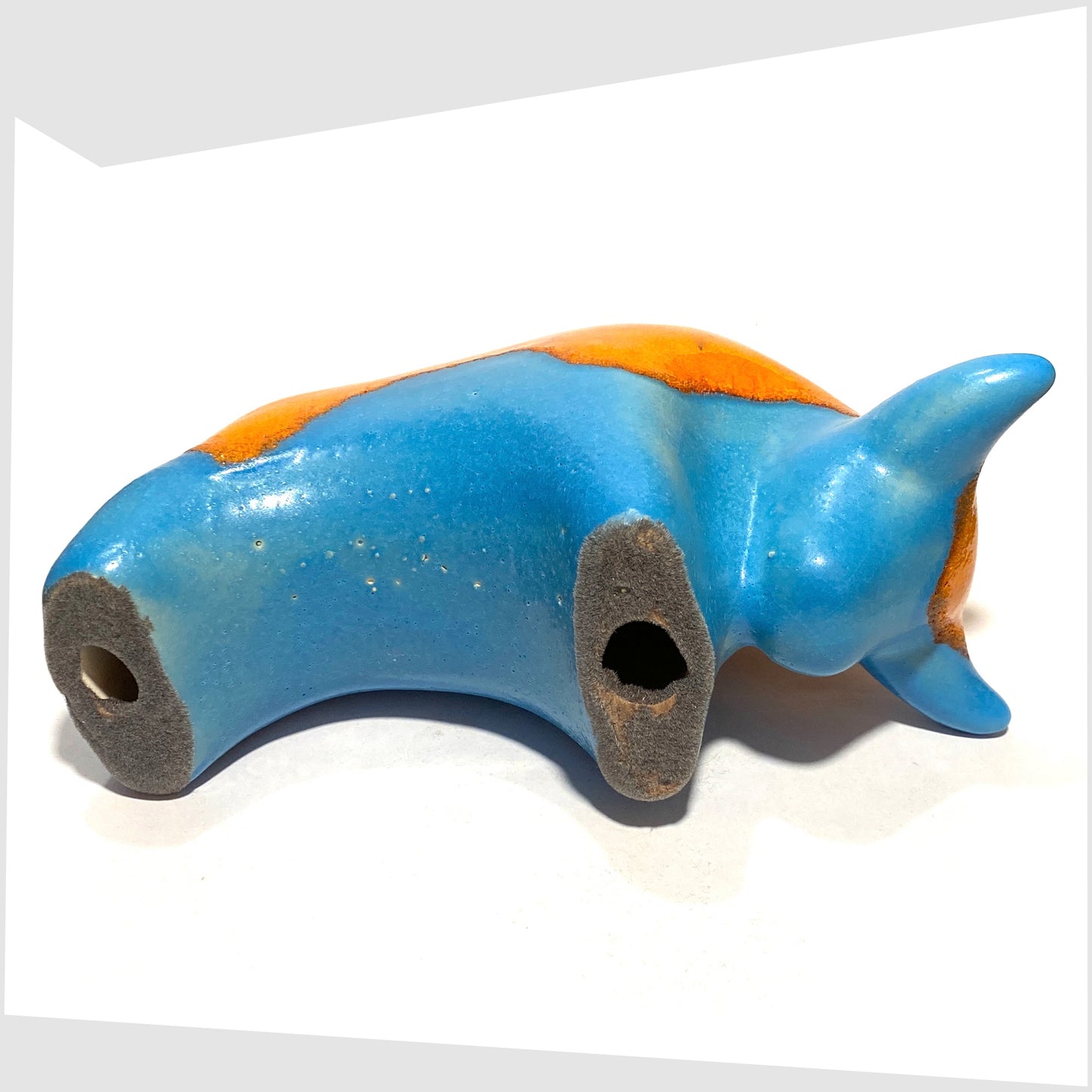 Underside of the Otto Keramik Ceramic Bull in Orange Over Blue glaze, shown on a white background
