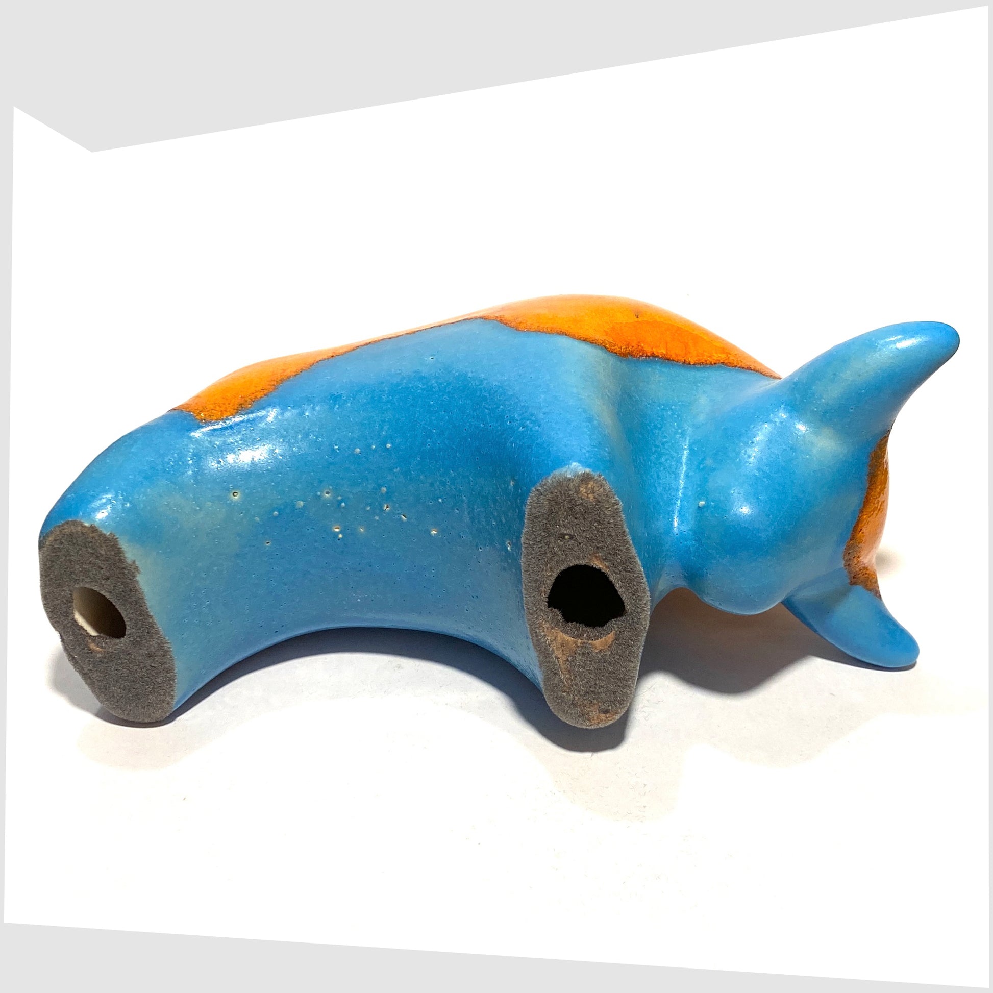 Underside of the Otto Keramik Ceramic Bull in Orange Over Blue glaze, shown on a white background