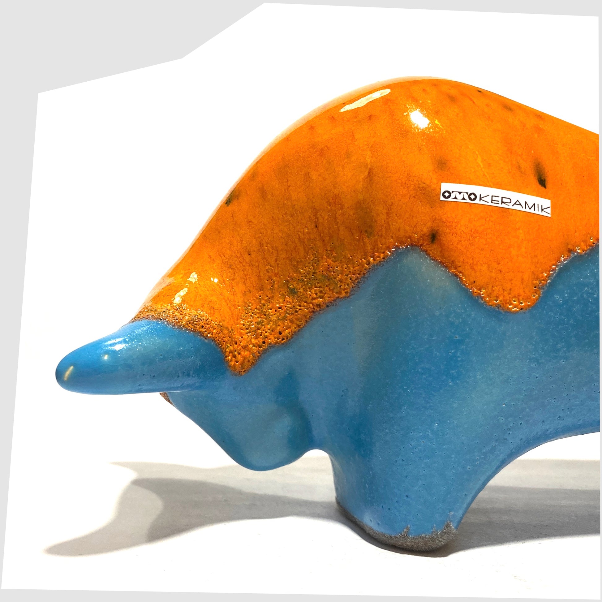 Close up of the Otto Keramik Ceramic Bull in Orange Over Blue glaze, shown on a white background