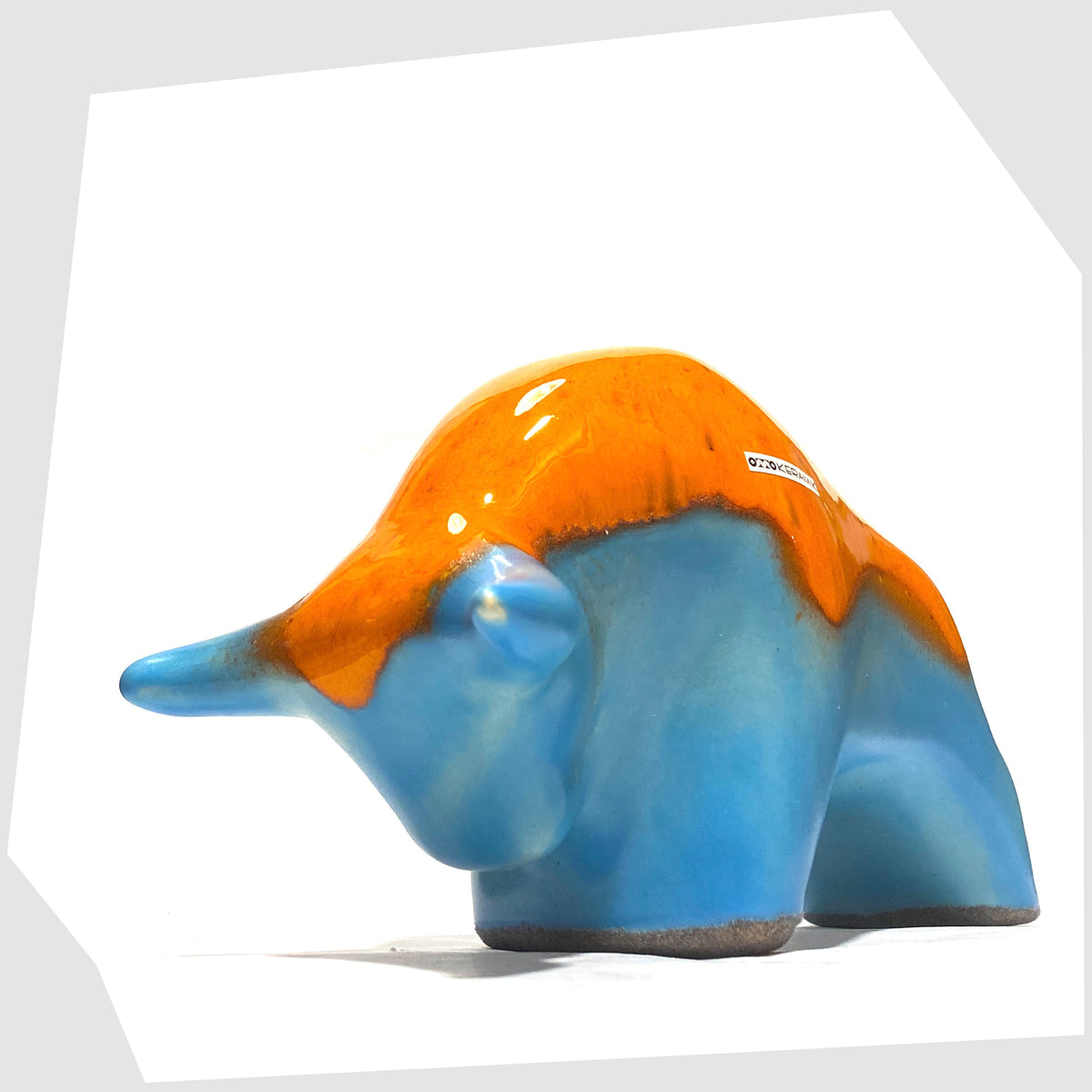 Front of the Otto Keramik Bull in orange over blue glaze, shown on a white background