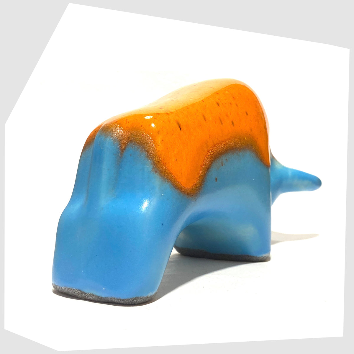 Rear of the Otto Keramik Bull in orange over blue glaze, shown on a white background