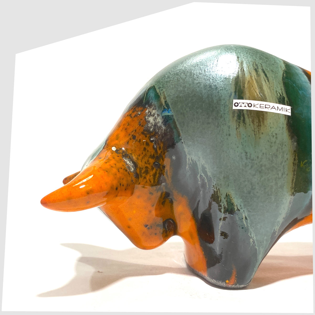 Close up of the Otto Keramik Bull in Peru Glaze of orange with sea green bands, shown on a white background