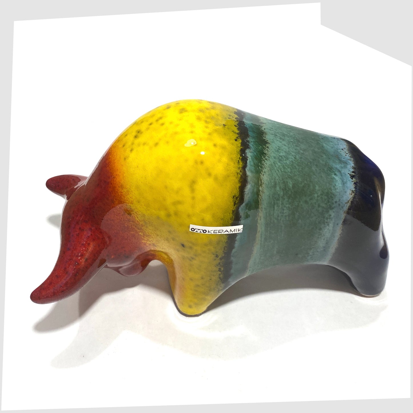 Overhead view of the Otto Keramik ceramic bull in rainbow glaze of multicoloured stripes, shown on a white background