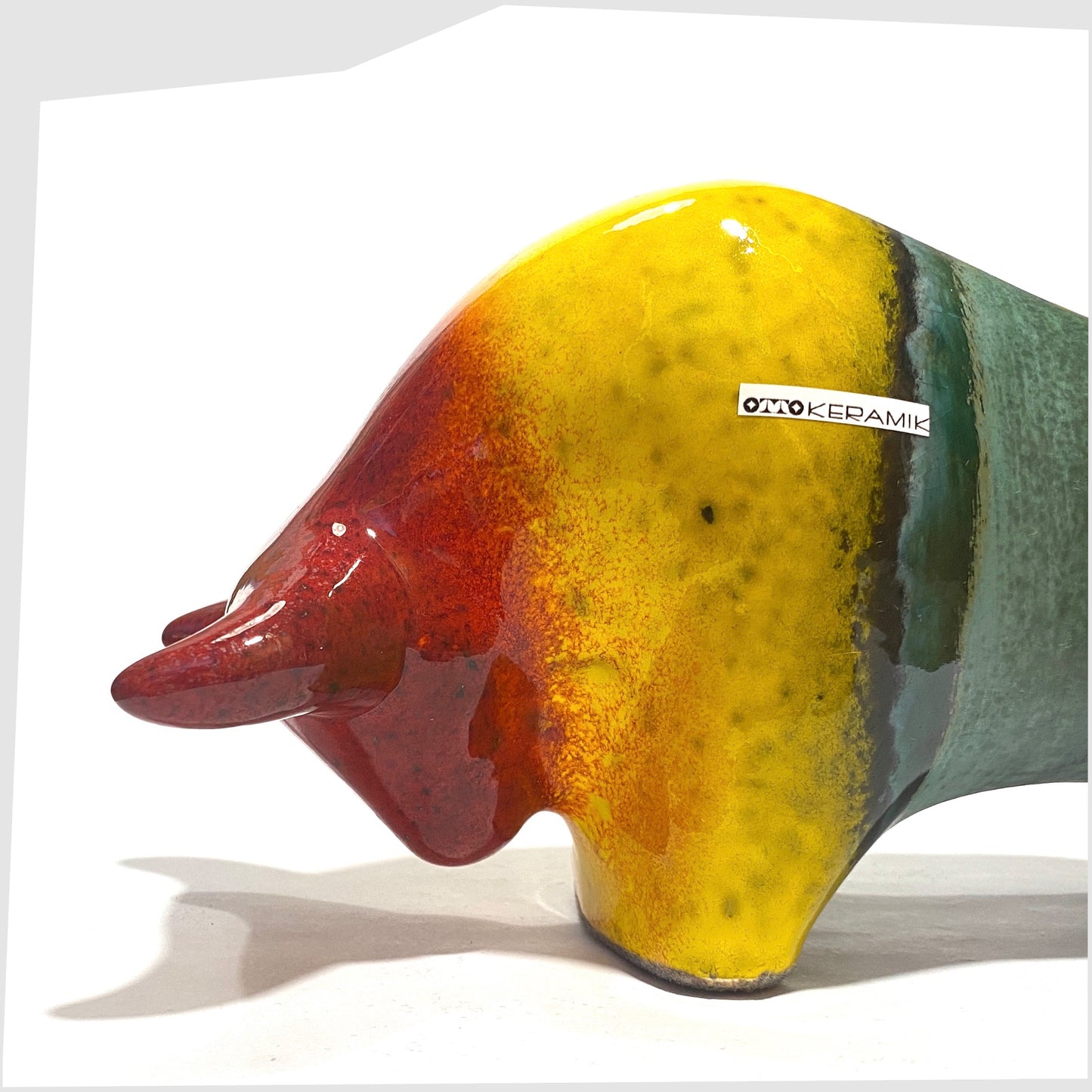 Close up of the front section of the Otto Keramik ceramic bull in rainbow glaze of multicoloured stripes, shown on a white background
