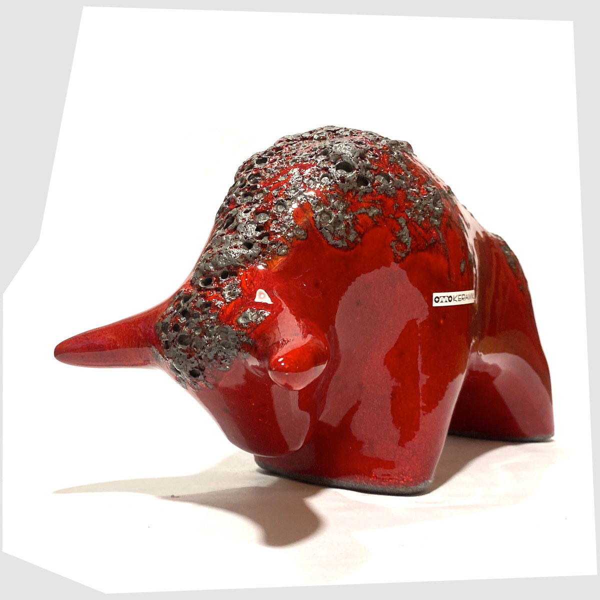 Front of the Otto Keramik ceramic bull in red fat lava glaze, bull shaped sculpture in red with grey fat lava along the spine, shown on a white background