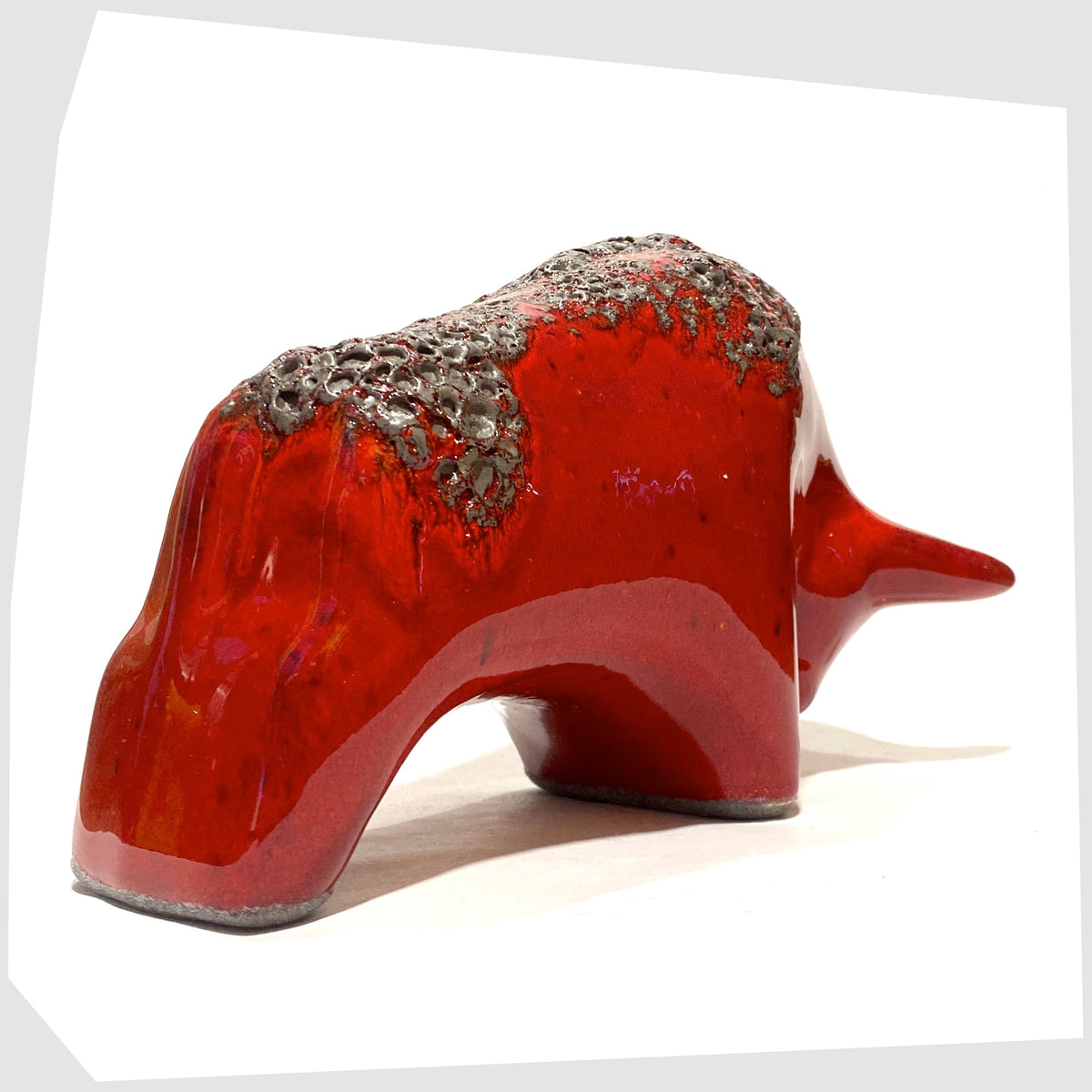 Rear of the Otto Keramik ceramic bull in red fat lava glaze, bull shaped sculpture in red with grey fat lava along the spine, shown on a white background