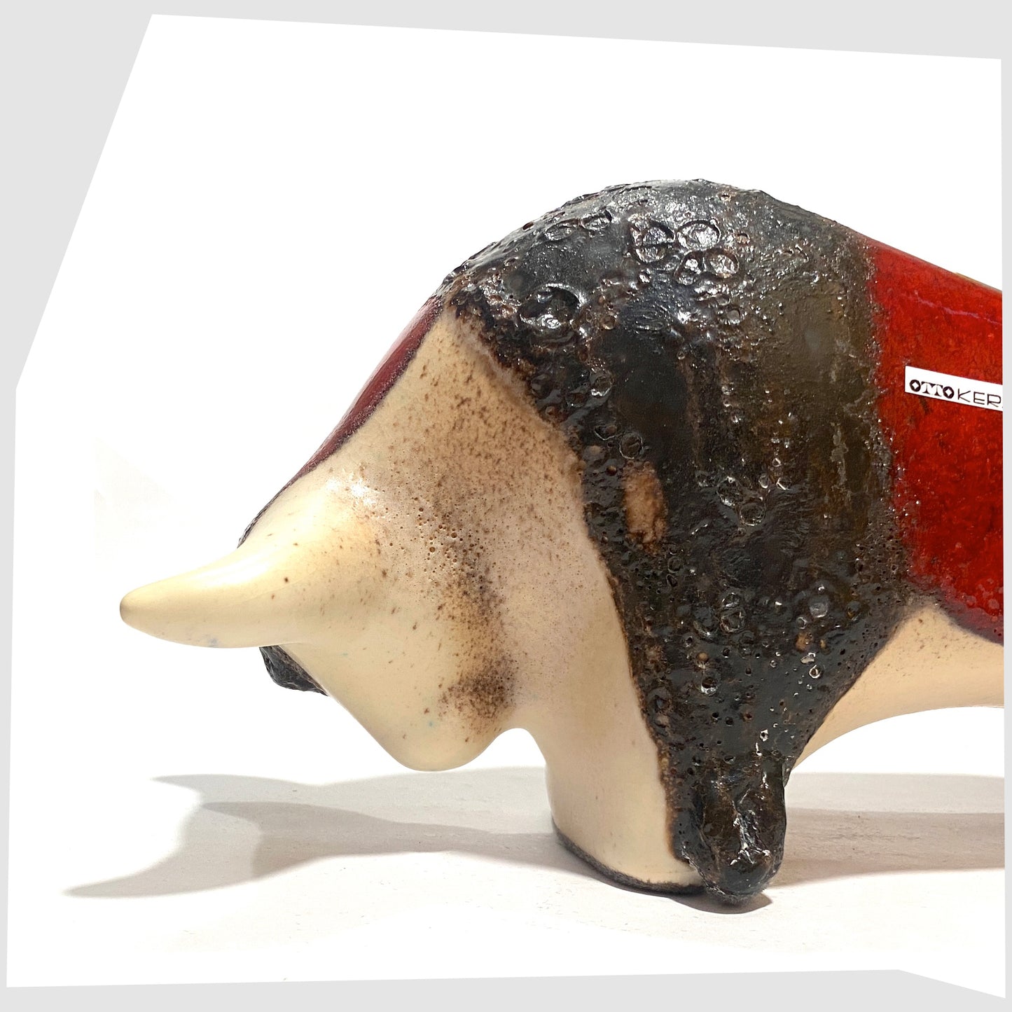 Close up of the Otto Keramik ceramic bull in cream and red glaze with bands of thick fat lava, shown on a white background