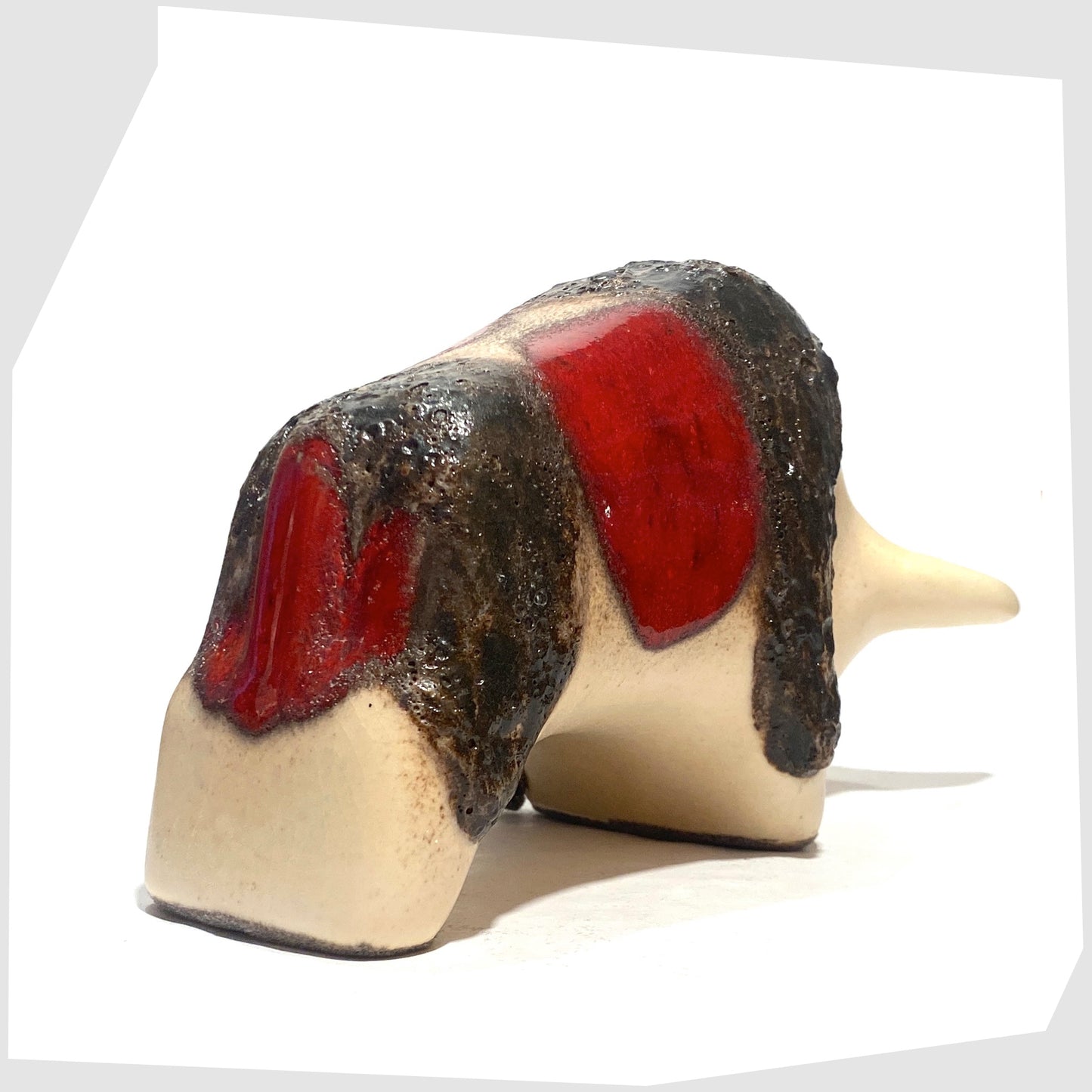 Rear of the Otto Keramik ceramic bull in cream and red glaze with bands of thick fat lava, shown on a white background
