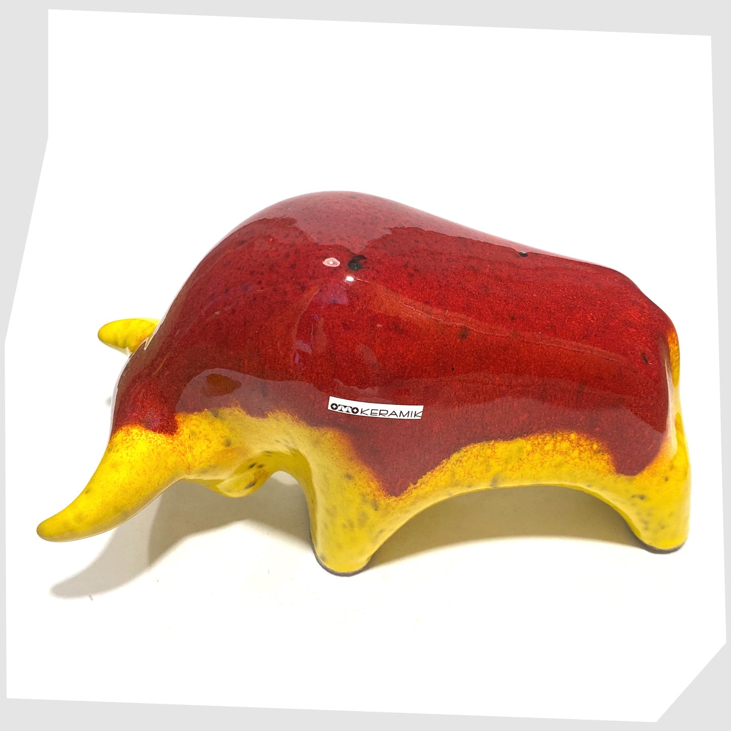 Back of the Otto Keramik Ceramic Bull in vibrant red over yellow glaze shown on a white background