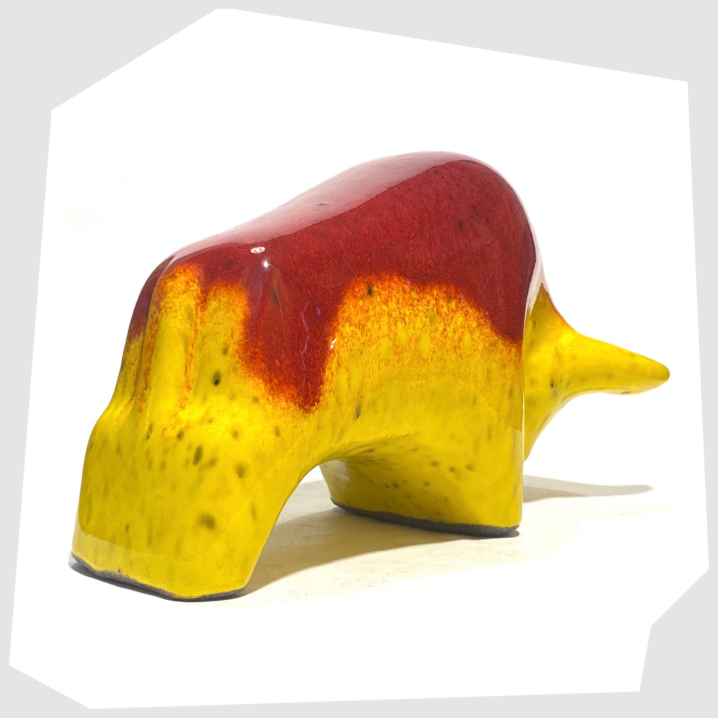 Rear of the Otto Keramik Ceramic Bull in vibrant red over yellow glaze shown on a white background