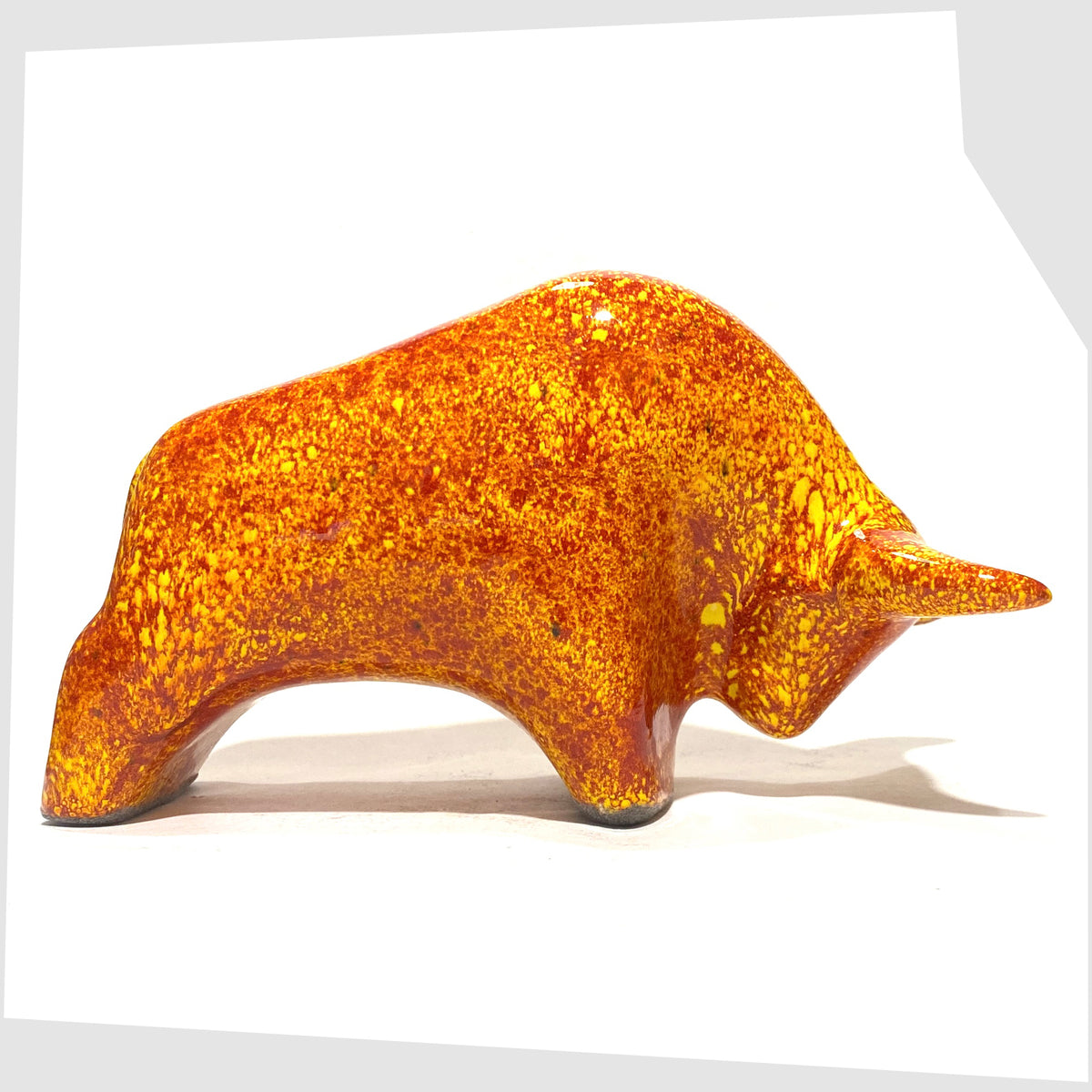 West German Pottery-style Otto Keramik Bull in fire glaze of red, orange and yellow flecks, shown on a white background