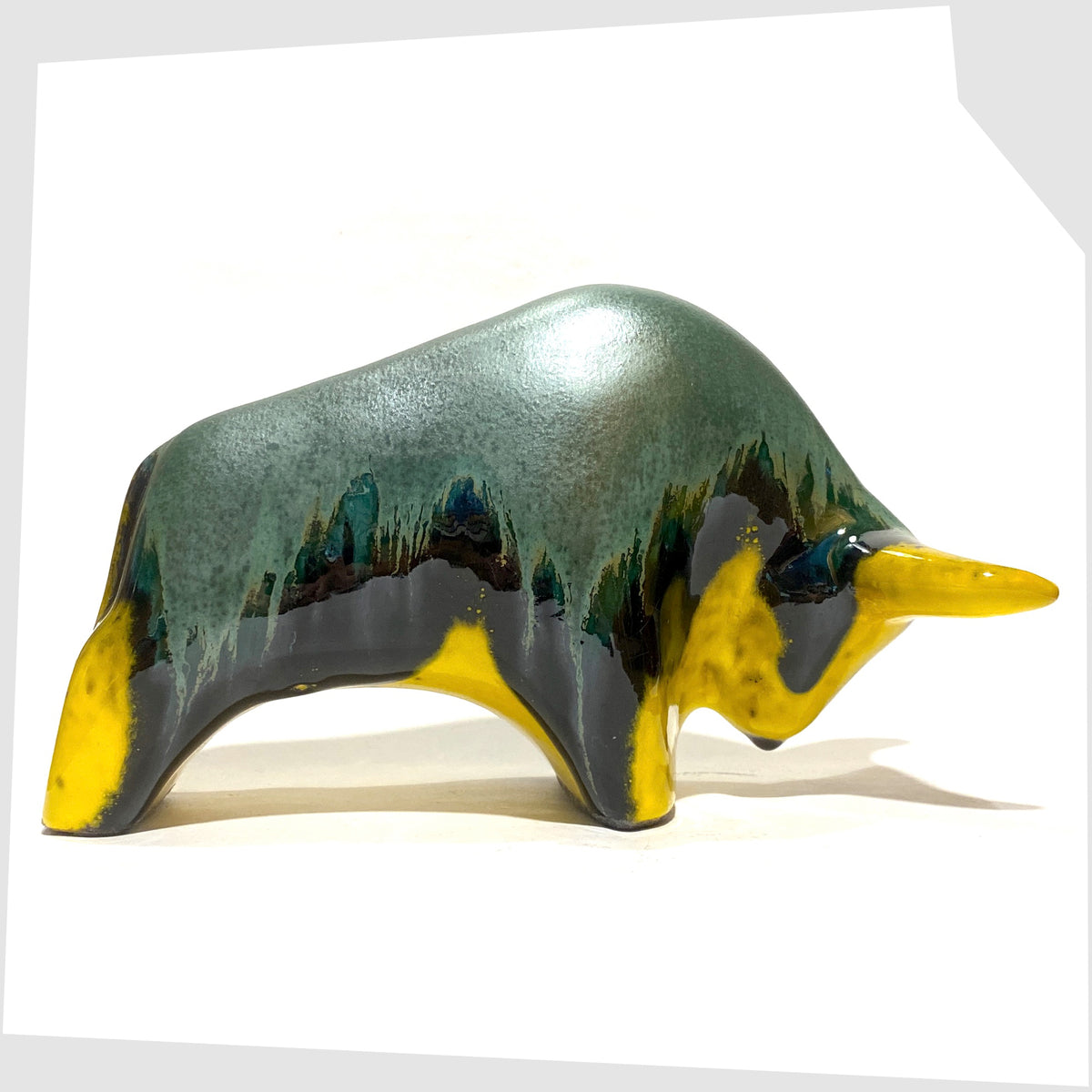 Side of the Otto Keramik ceramic bull-shaped sculpture in green over yellow drip glaze, shown on a white background