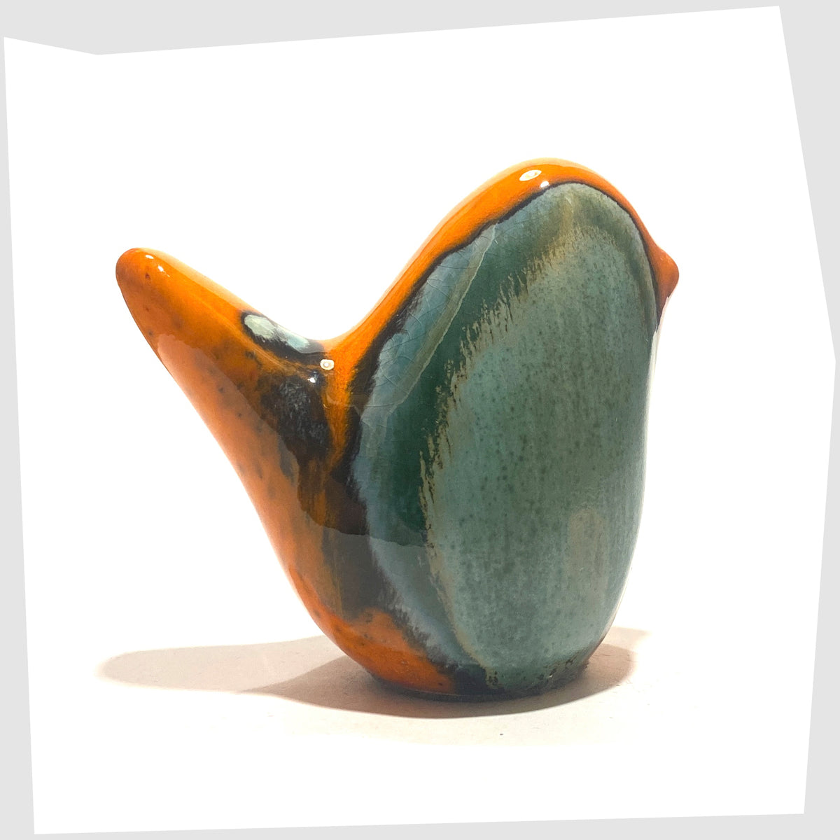 West German Pottery-style Otto Keramik Ceramic Bird in Peru glaze of orange with sea green drip glaze, shown on a white background