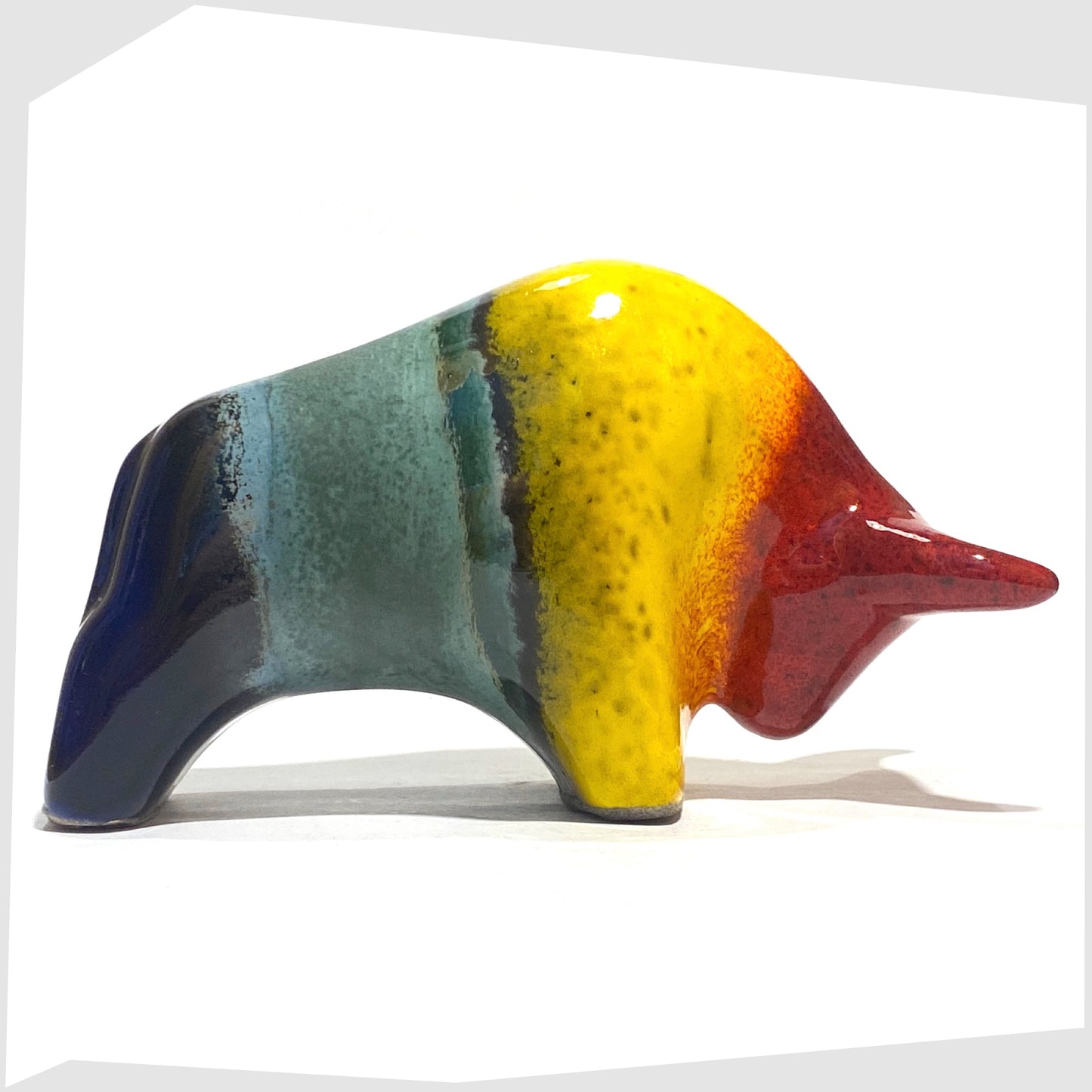 Otto Keramik ceramic bull shaped ornament in rainbow glaze of multicoloured stripes, shown on a white background