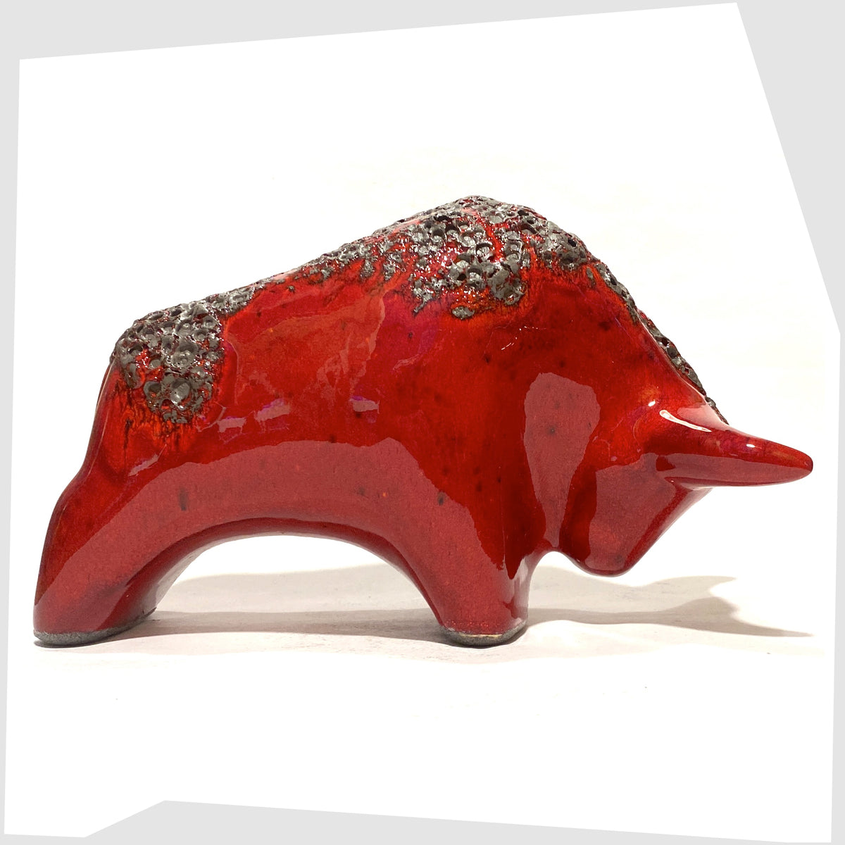 Side of the Otto Keramik ceramic bull in red fat lava glaze, bull shaped sculpture in red with grey fat lava along the spine, shown on a white background