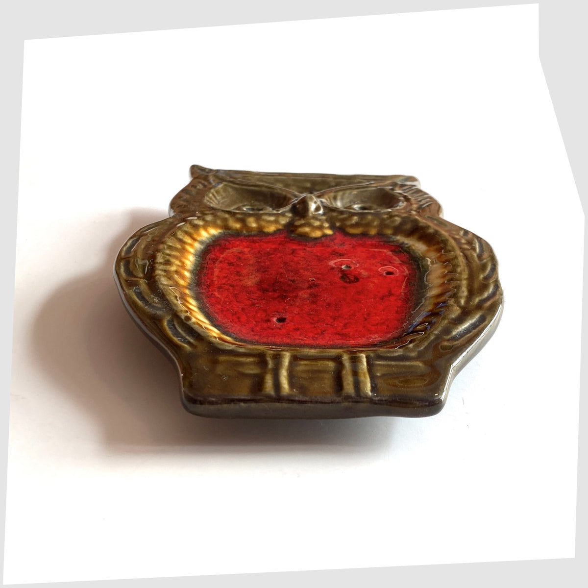 Side profile of the Mid-century ceramic owl shaped spoon rest with volcanic red glaze, shown on a white background