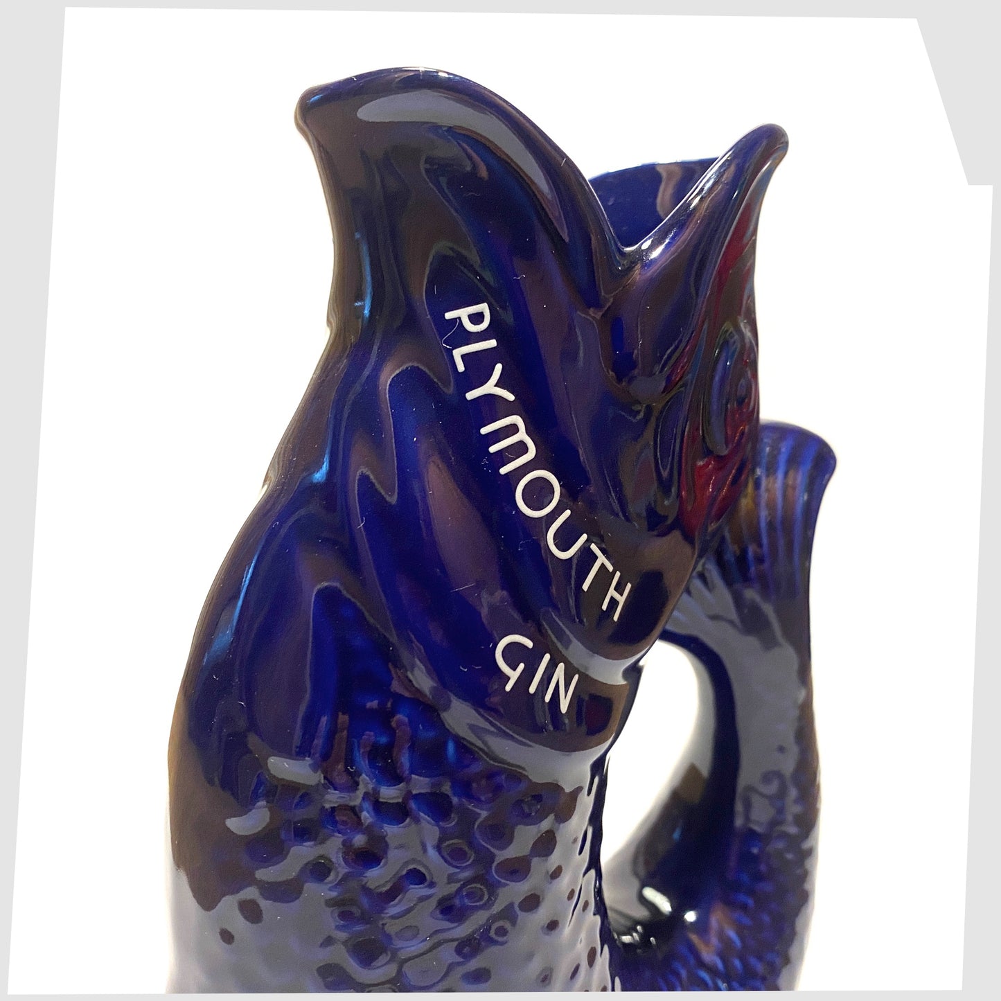close up of the artefact of wade ceramics, plymouth gin gluggle jug in cobalt blue glaze with white text