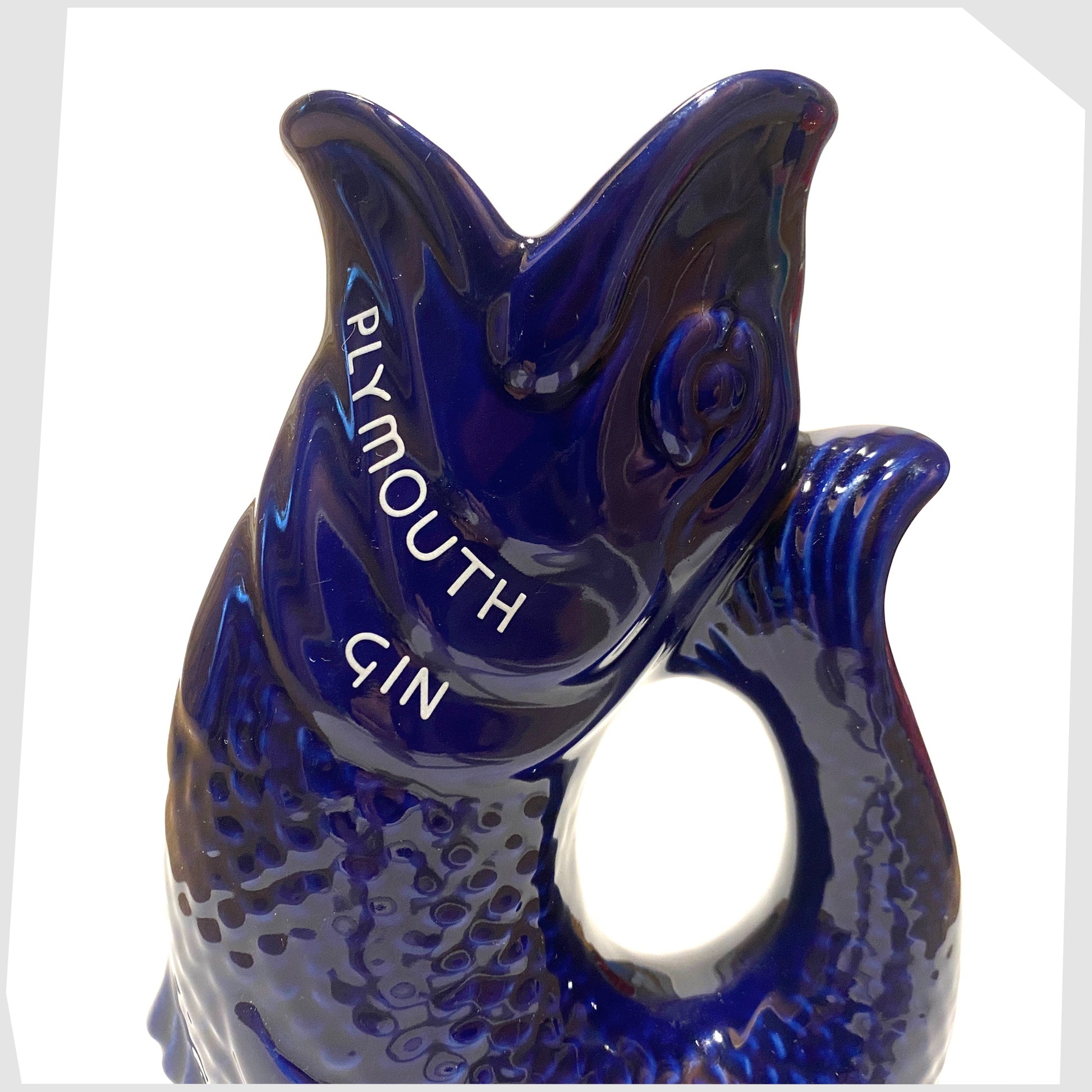 close up of the artefact of wade ceramics, plymouth gin gluggle jug in cobalt blue glaze with white text