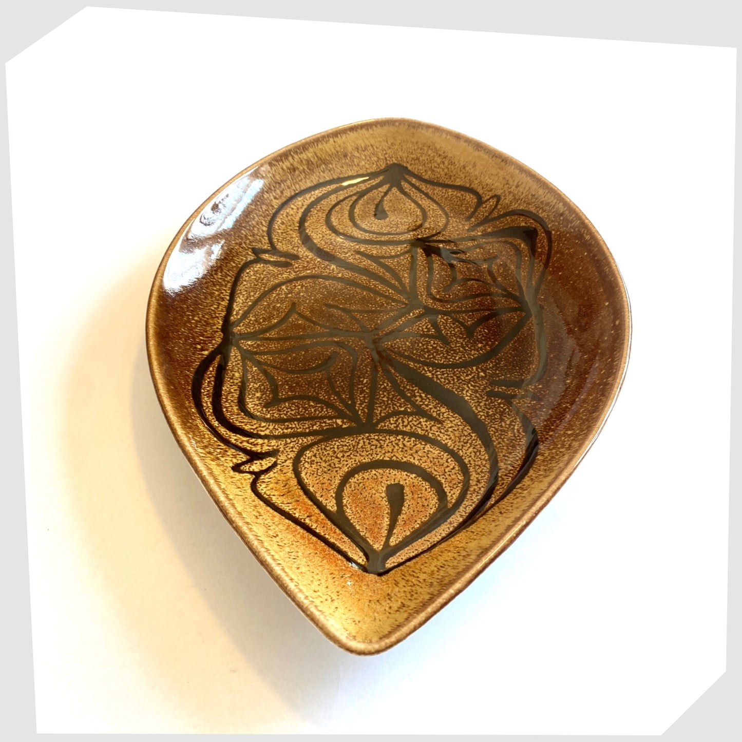 poole pottery teardrop shaped dish, decorated with black flowing lines on an amber and brown glaze