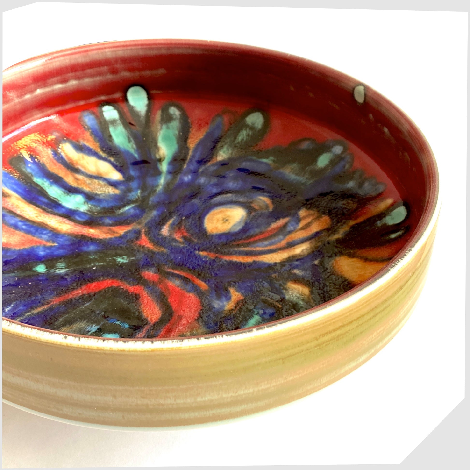 side profile of the large Poole Pottery 11" Bowl in an artistic Delphis glaze of red, cobalt blue and turquoise