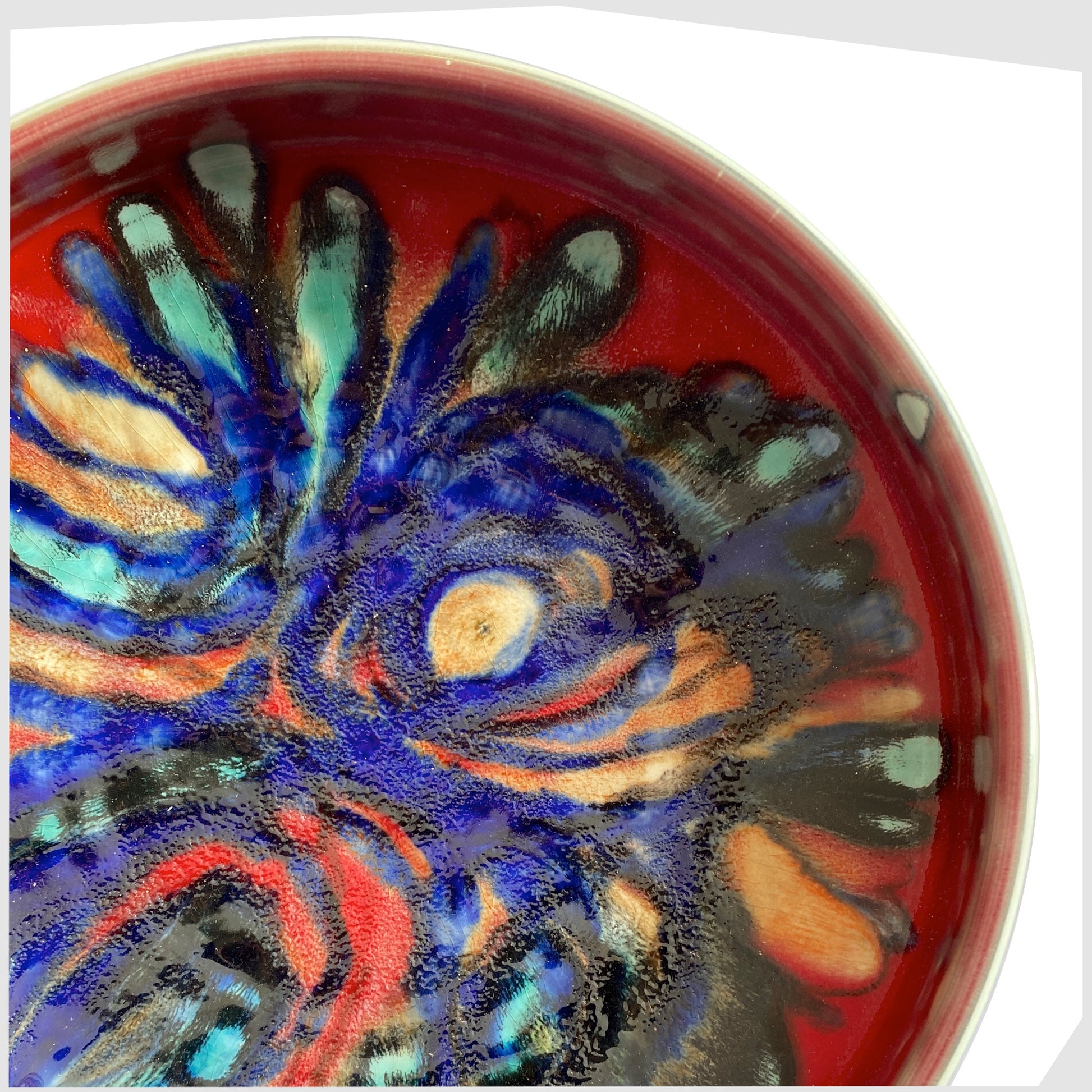 close up of the large Poole Pottery 11" Bowl in an artistic Delphis glaze of red, cobalt blue and turquoise
