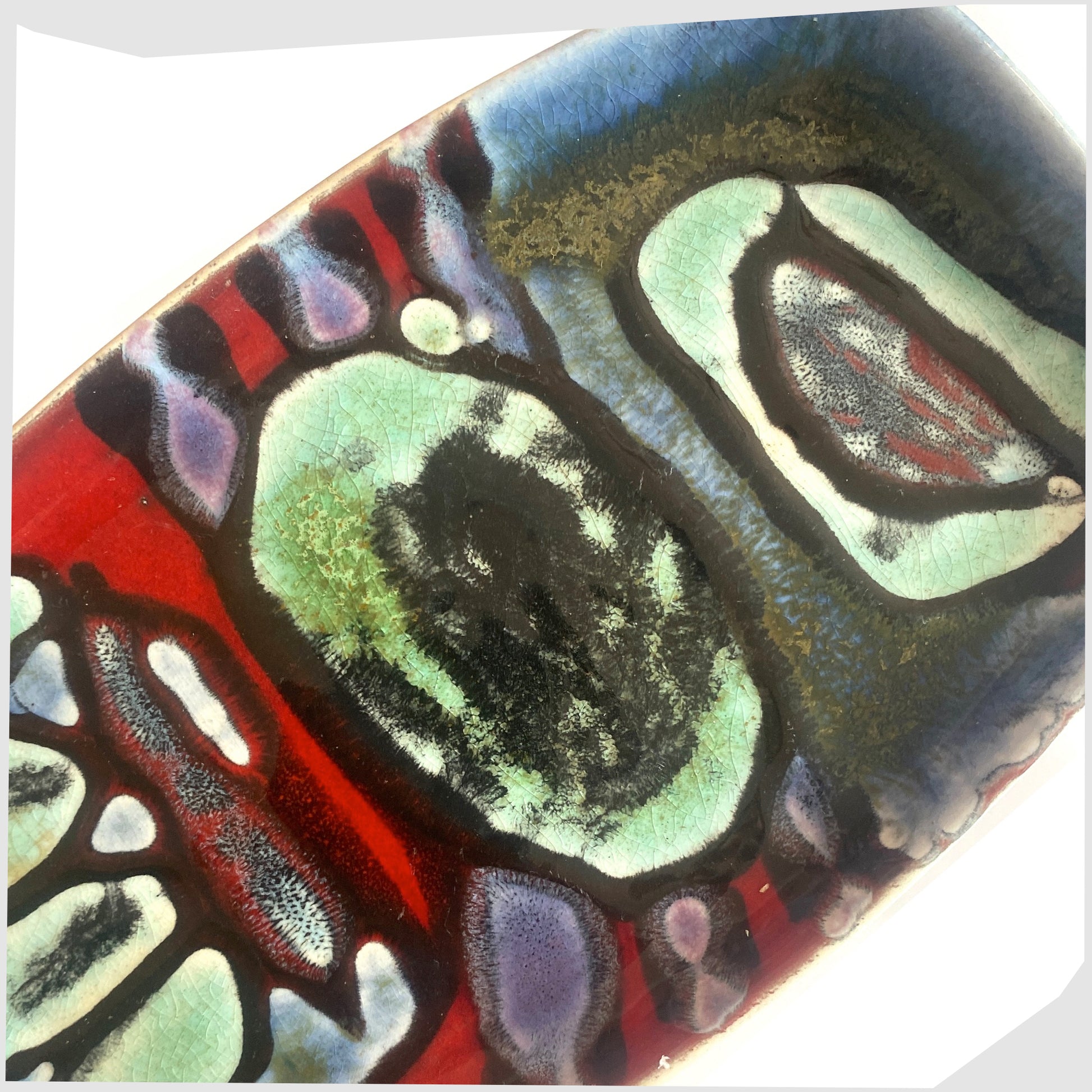 close up of the Poole Pottery Delphis Pin Dish, Shape 361, by Angela Wyburgh in an artistic multicoloured glaze of red, blue and turquoise