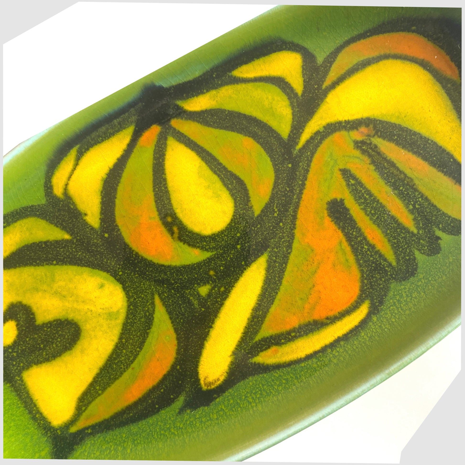 close up of the Poole Pottery Delphis Dish, Shape 361 by Cynthia Bennett in a green glaze with yellow and orange forms