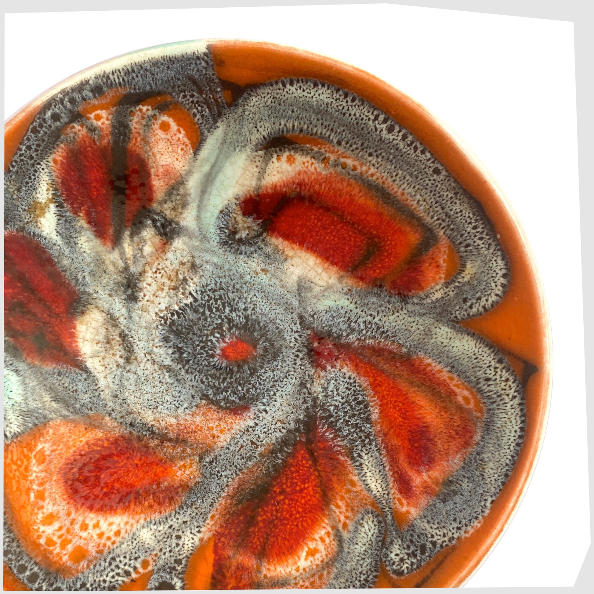 Close up of the Poole Pottery Delphis Pin Dish by Jean Millership finished in a vibrant orange, blue and red glaze