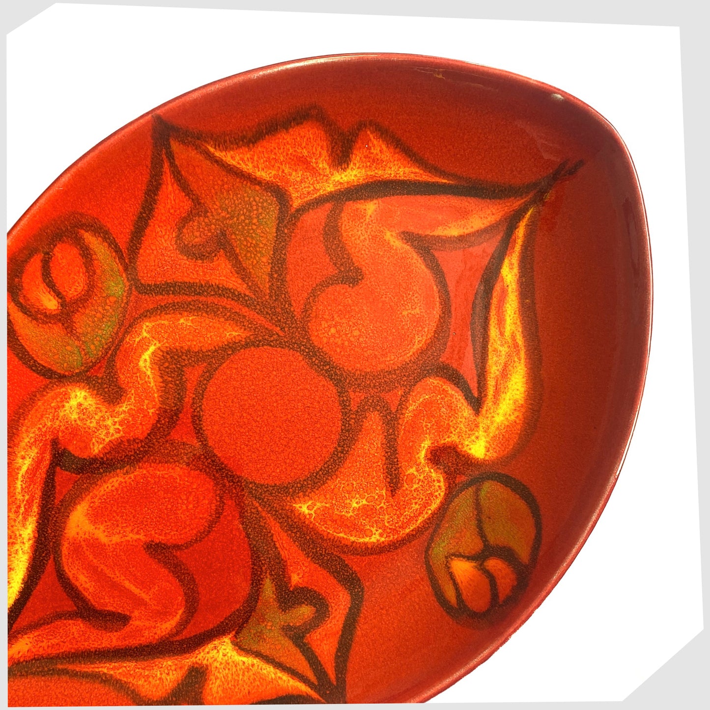 close up of the poole pottery teardrop dish finished in a red delphis glaze with orange and green fluid forms