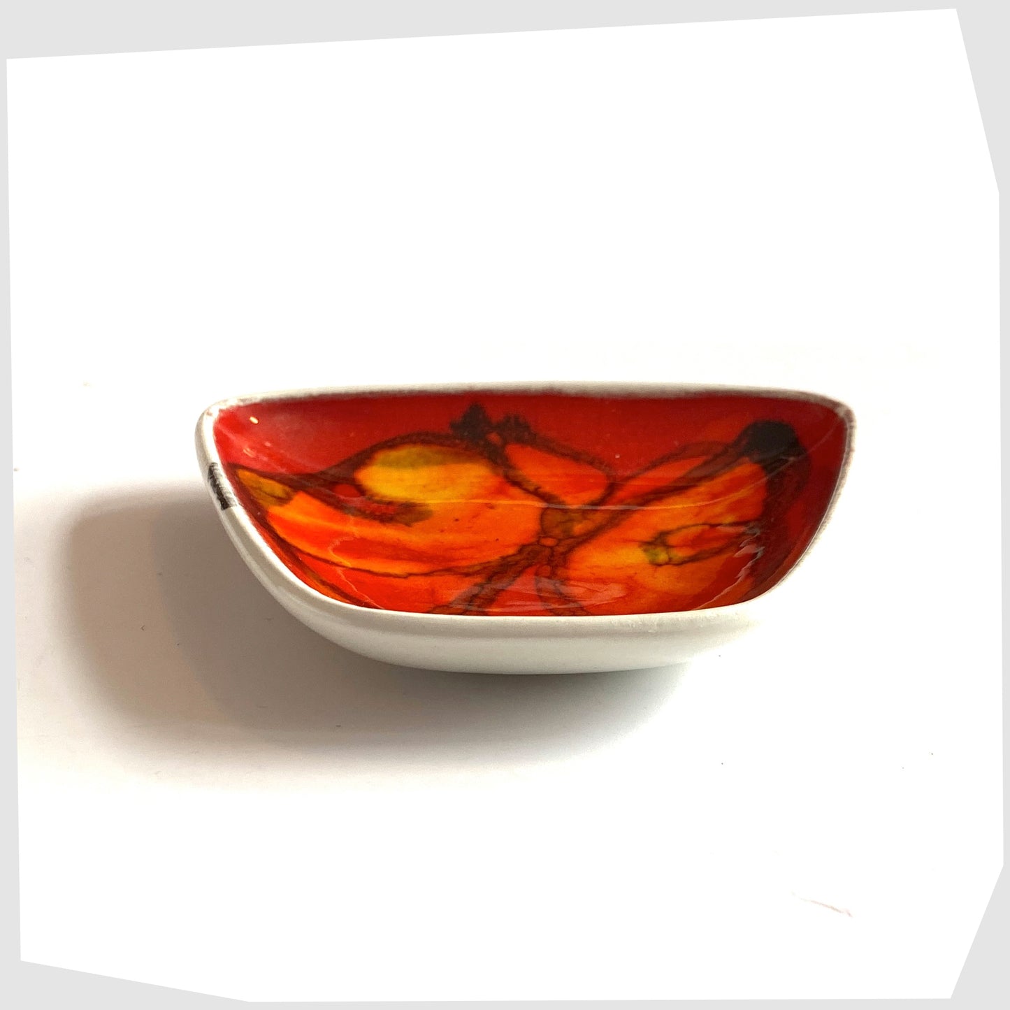 side of the Poole Pottery Delphis Pin Dish by Anita Lawrence in a red glaze with orange and yellow shapes