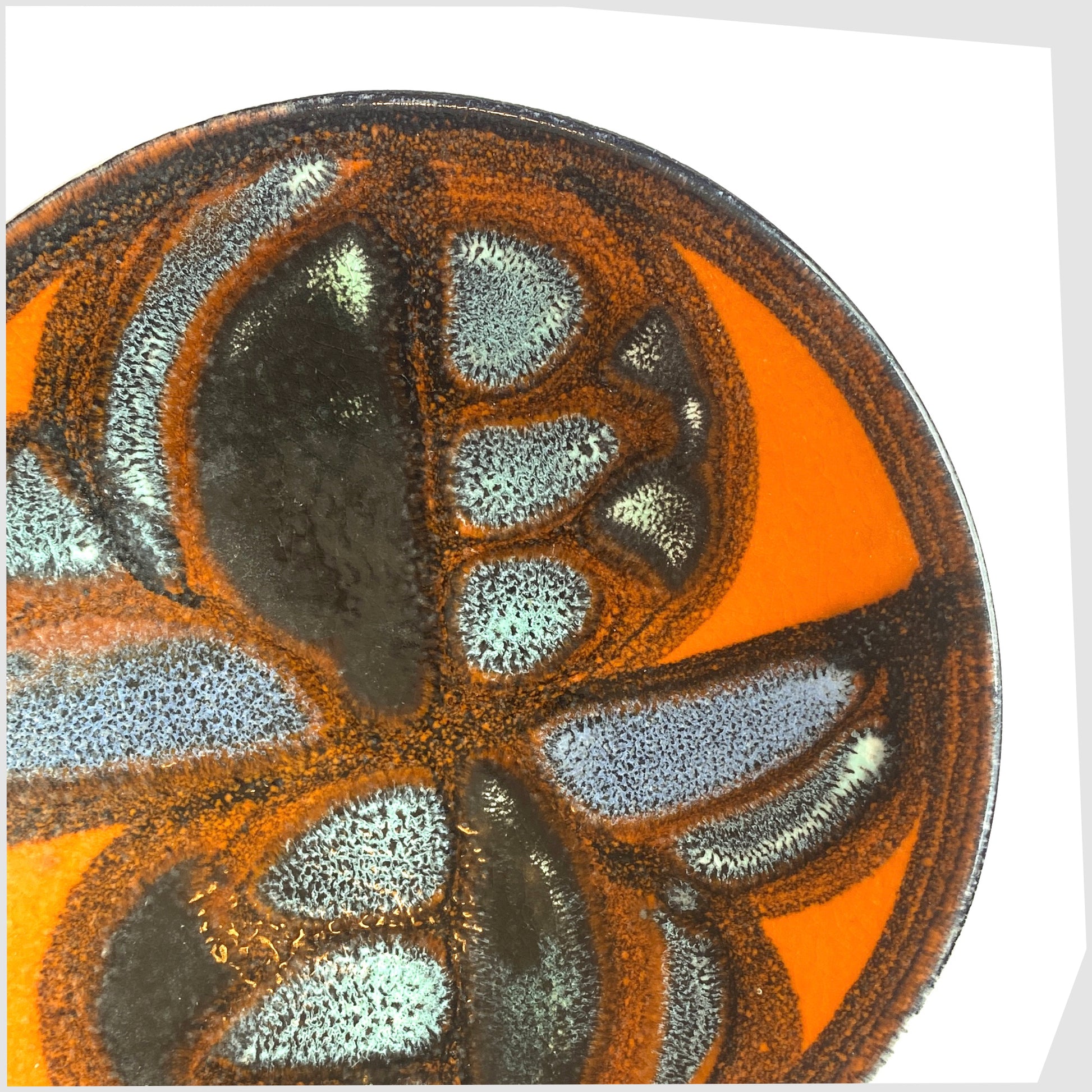 close up of the Poole Pottery Delphis Pin Dish, Shape 49, finished in a rich orange glaze with blue and turquoise forms